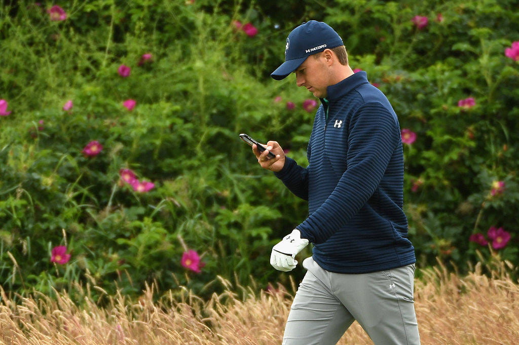 Jordan Spieth watches his phone